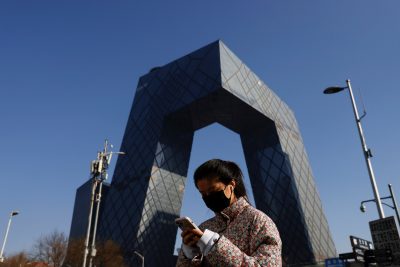 A woman holding a mobile phone walks past the CCTV headquarters, the home of Chinese state media outlet CCTV and its English-language sister channel CGTN, in Beijing, China, 5 February 2021 (Photo: REUTERS/Carlos Garcia Rawlins).