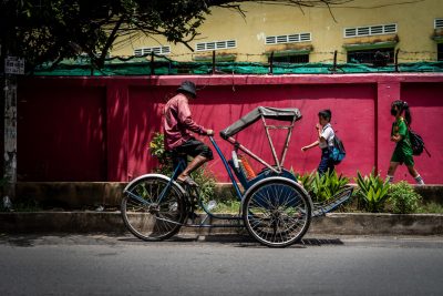 A bicycle taxi rider stops to pick fresh herbs along a busy road in Phnom Penh. (Photo: Reuters/ Matt Hunt)