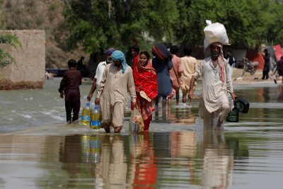 Residents walk amid flood water as they head to their villages, following rains and floods during the monsoon season in Sehwan, Pakistan, 6 September, 2022 (Photo: Reuters/Akhtar Soomro).