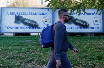 A man passes by government billboards that read: 'Brussels sanctions are destroying us', depicting EU sanctions as a bomb, in Budapest, Hungary, 19 October 2022 (Photo: Reuters/Bernadett Szabo)