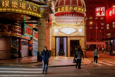 People wearing face masks walk under neon lights near casinos during the coronavirus disease (COVID-19) pandemic in Macau, China, 29 December 2022 (Photo:REUTERS/Tyrone Siu)