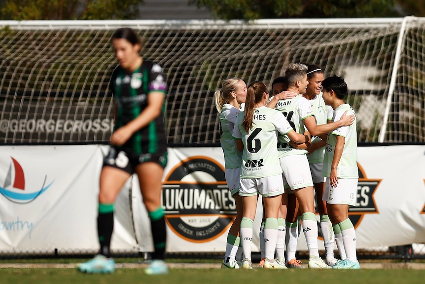 A soccer team wearing light green and white hug in a circle during a game