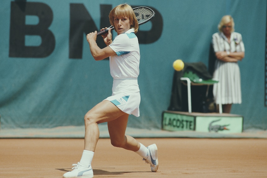 Martina Navratilova moves to her right on a claycourt with her racquet raised after playing a backhand. 