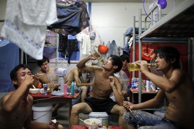 Migrant construction workers drink beer during a meal inside their dormitory after a shift at a residential construction site in Shanghai, China, 2 July 2013 (Photo: Reuters/Aly Song).