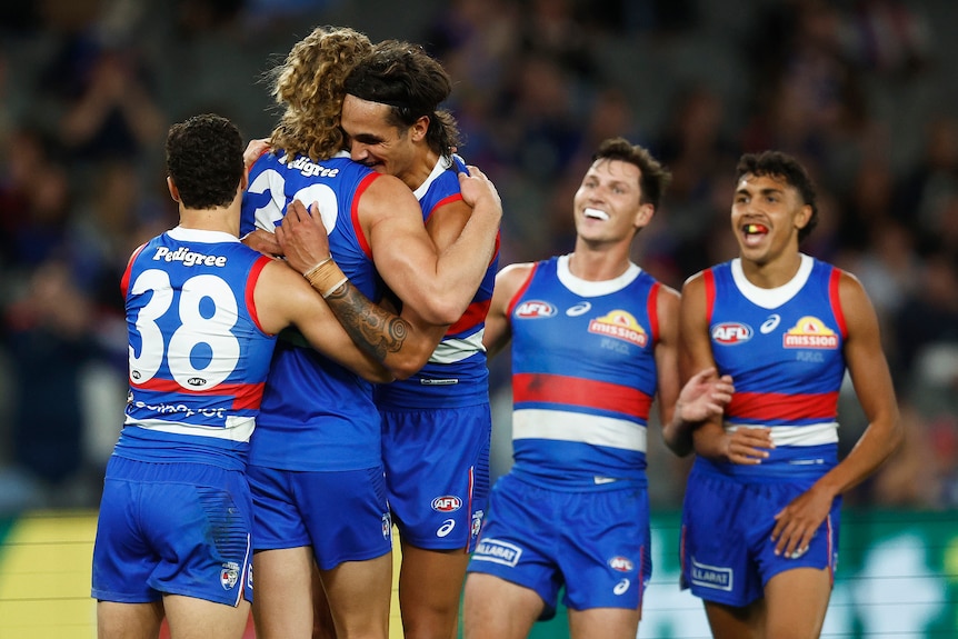 Jamarra Ugle-Hagan hugs Aaron Naughton as other Bulldogs players approach