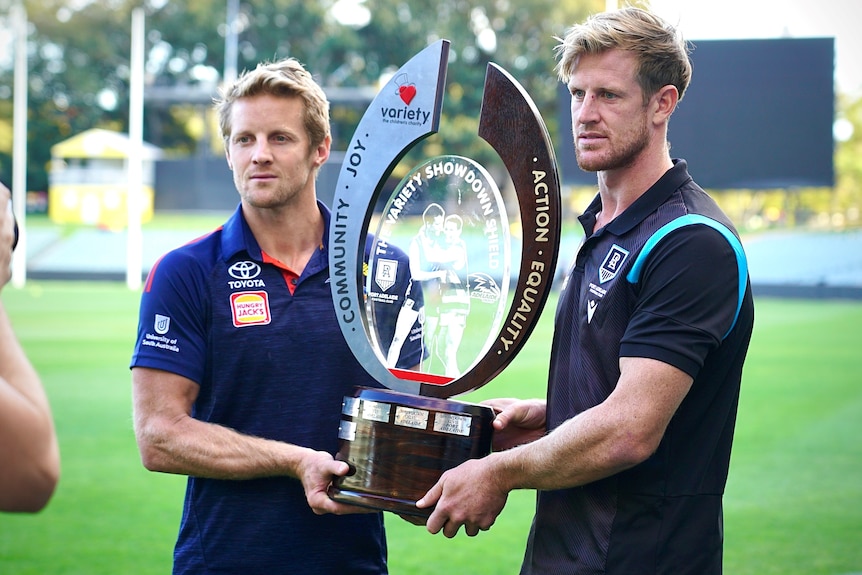 Two men holding a large trophy on an oval 