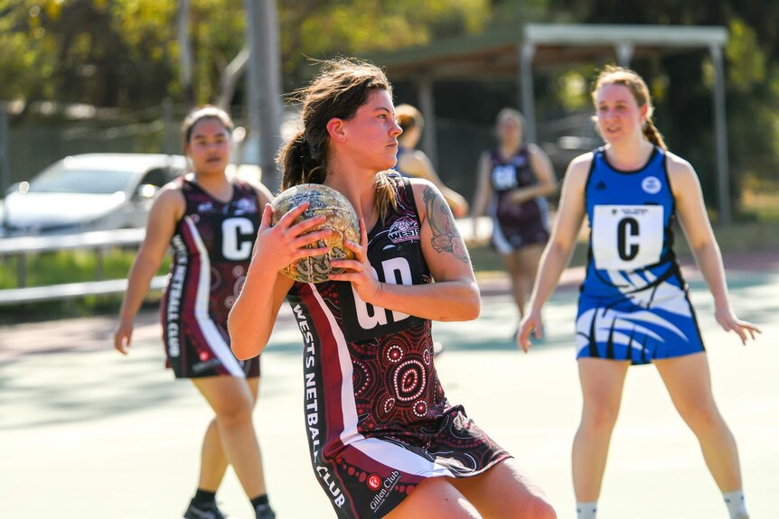 Two netball teams play on an outdoor court