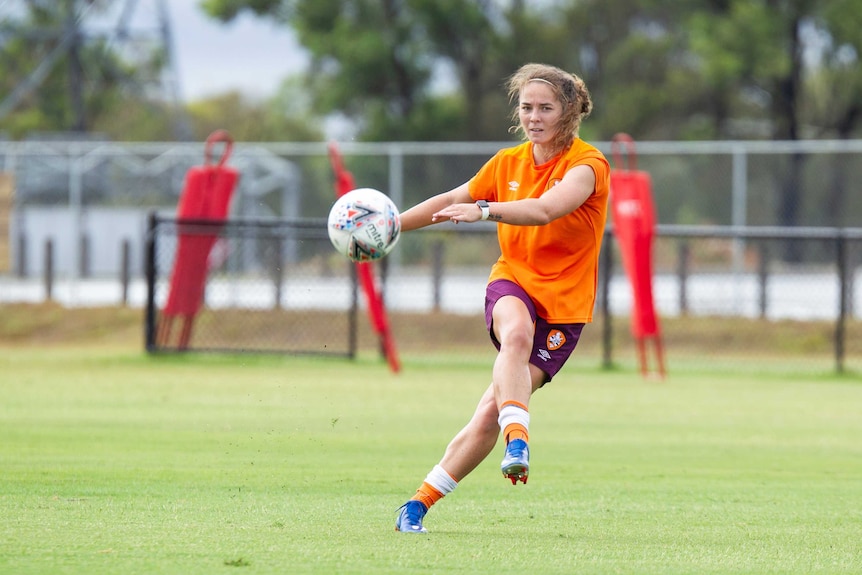 Jenna McCormick kicks a ball towards the camera, standing on one leg