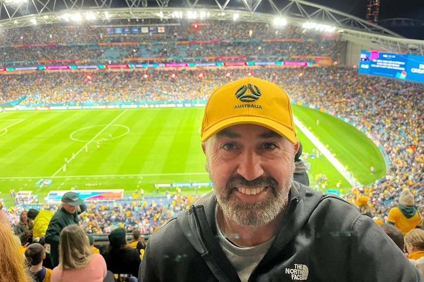 A man wearing an Australia-branded cap at a football stadium