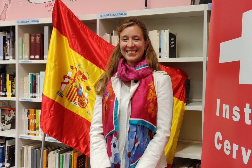 A woman standing with flag of Spain in a library