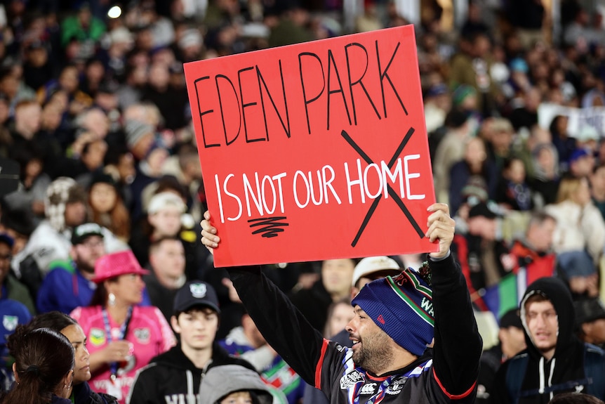 A Warriors fan holds up a sign saying "Eden Park is not our home" during an NRL game against the Dragons.