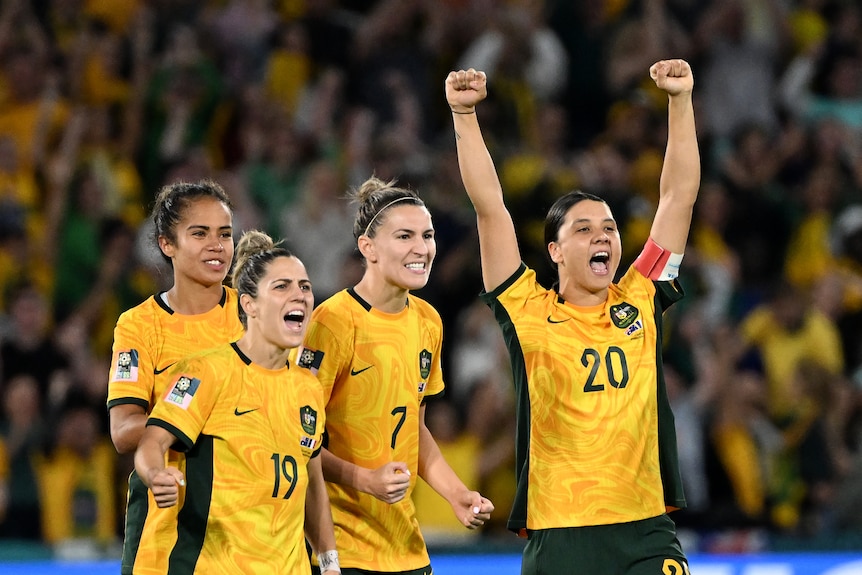 Matildas players cheer reacting to a penalty shoot out in a large stadium