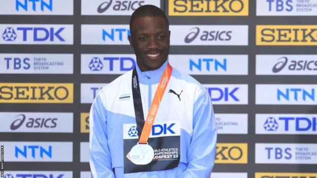 Letsile Tebogo stands in Botswana tracksuit with silver medal around his neck