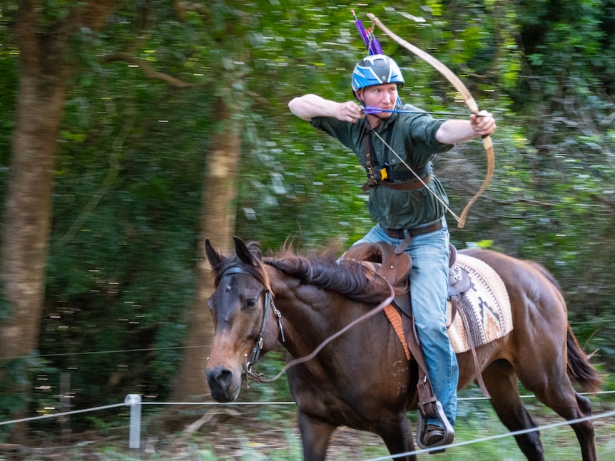 Young man on horseback with bow drawn and arrow loaded