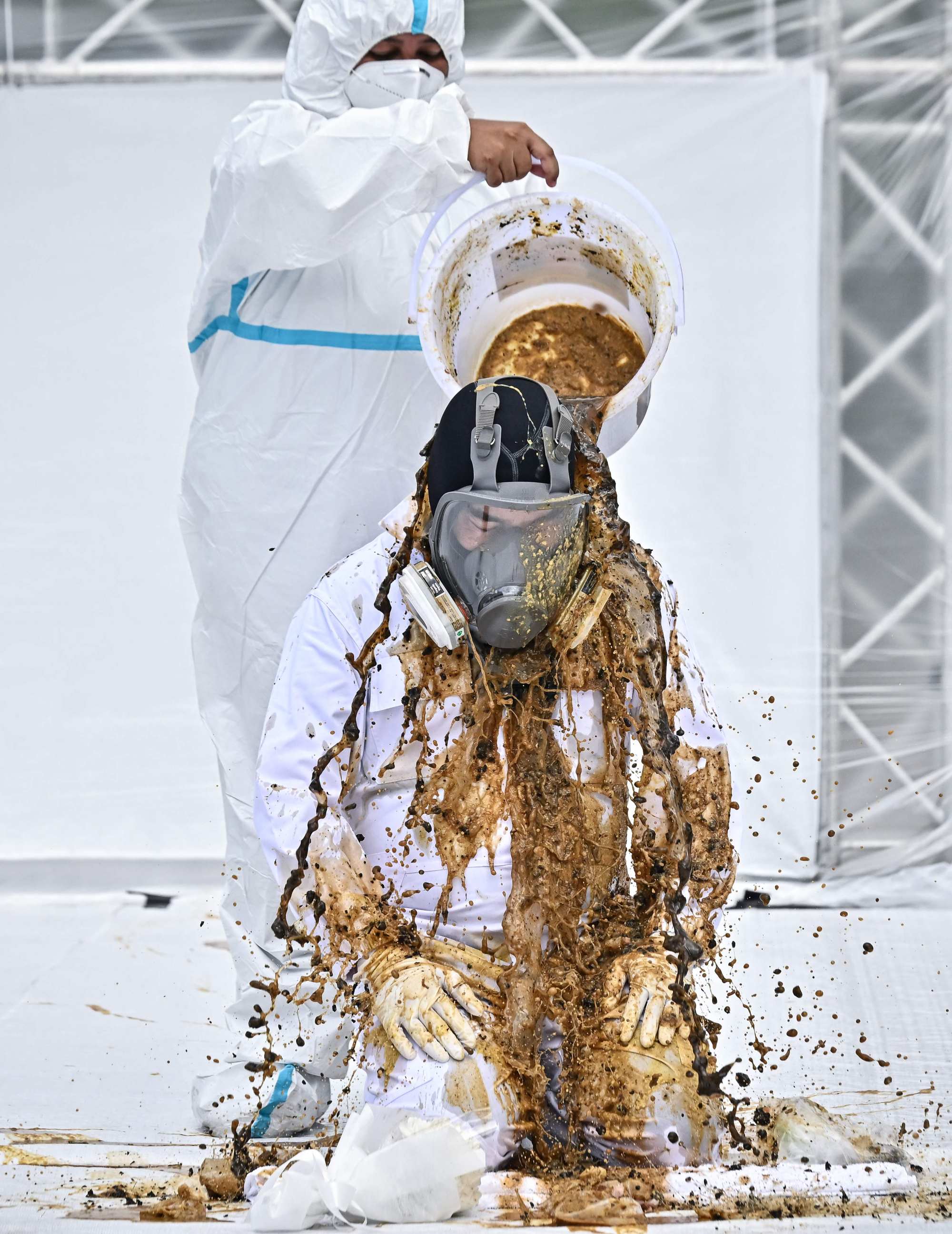 Duangrit Bunnag has a bucket of cow dung thrown at him in response to Pheu Thai’s inclusion of pro-establishment parties and the exclusion of the progressive Move Forward party. Photo by Lillian Suwanrumpha/AFP
