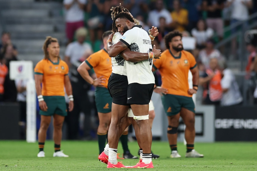 Two Fiji players embrace after defeating the Wallabies at the 2023 Rugby World Cup.
