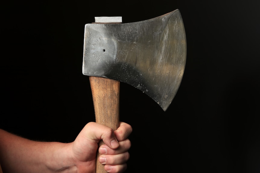 A man's hand holds an axe.