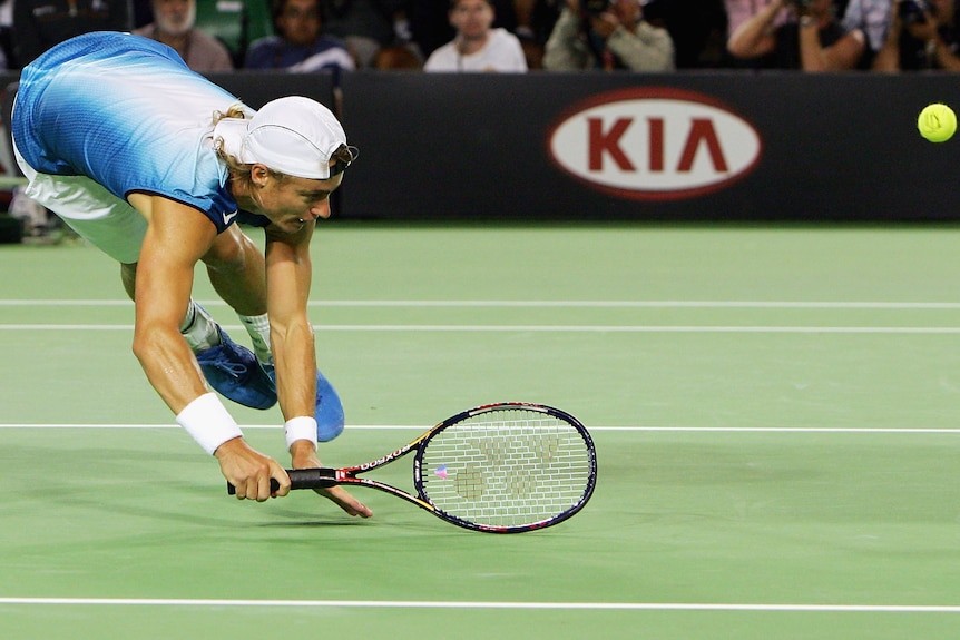 Australian tennis player Lleyton Hewitt tumbles to teh court after trying to hit a diving volley in a match.