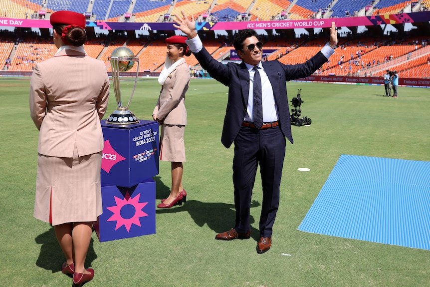 Sachin Tendulkar waves after carrying the Cricket World Cup trophy into Narendra Modi Stadium.