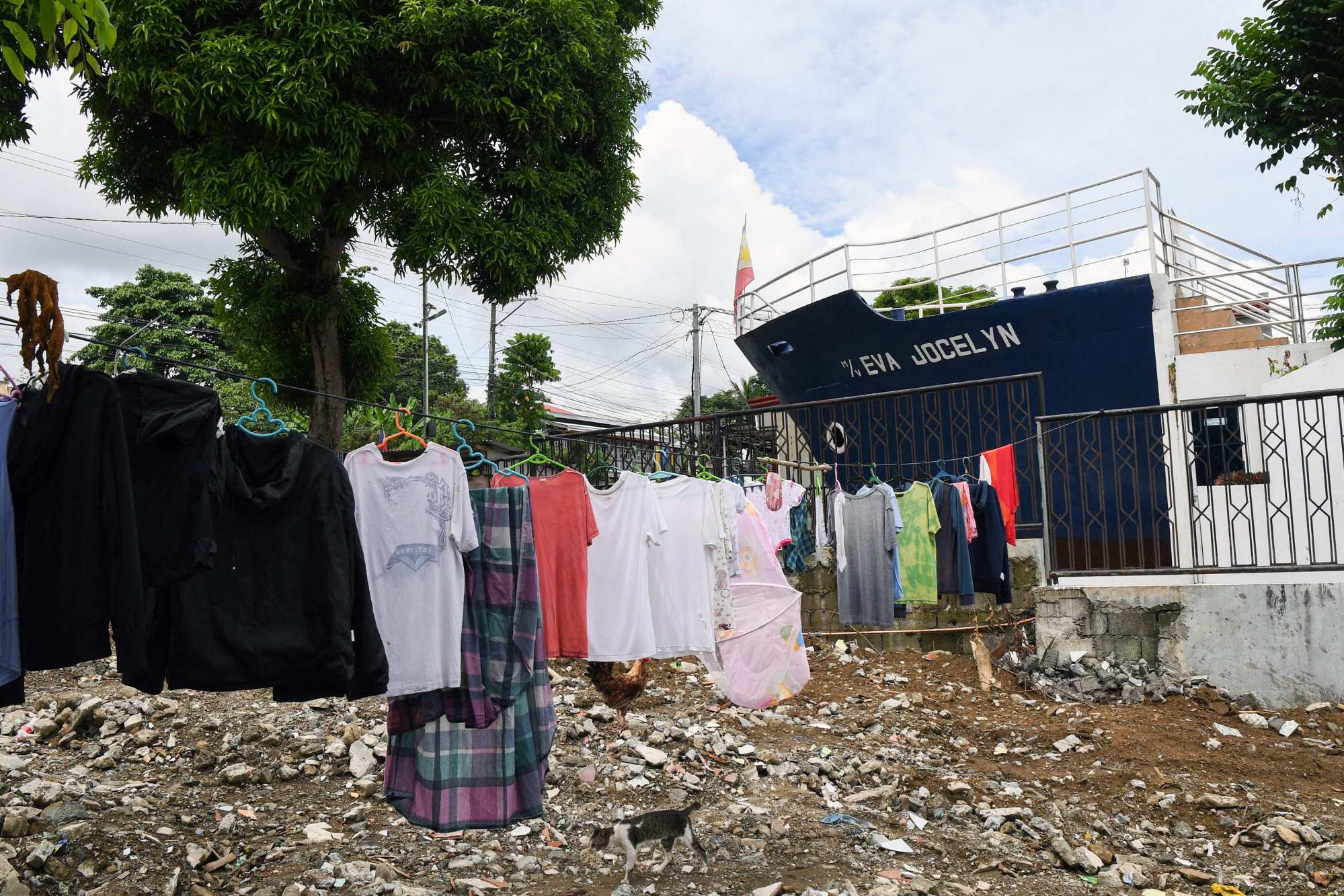 Laundry on a clothes line over an empty lot beside the bow of a cargo ship (background), preserved as a memorial for the village dead from Super Typhoon Haiyan, in Tacloban city’s Anibong district, Leyte province. Photo: AFP