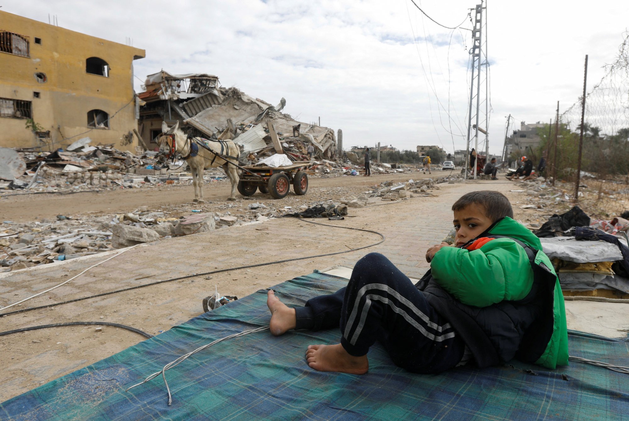 A Palestinian boy rests on a mattress near the ruins of his house which was destroyed by Israeli strikes during the conflict, amid a temporary truce between Israel and Hamas. Photo: Reuters