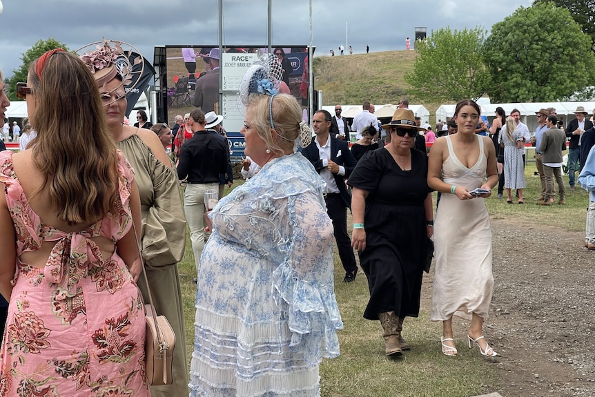 A group of woman talking wearing colourful dresses in front of Bowral Showground track