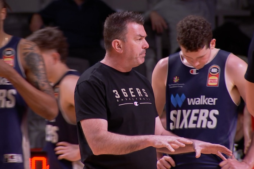 A man giving instructions to male basketball players.