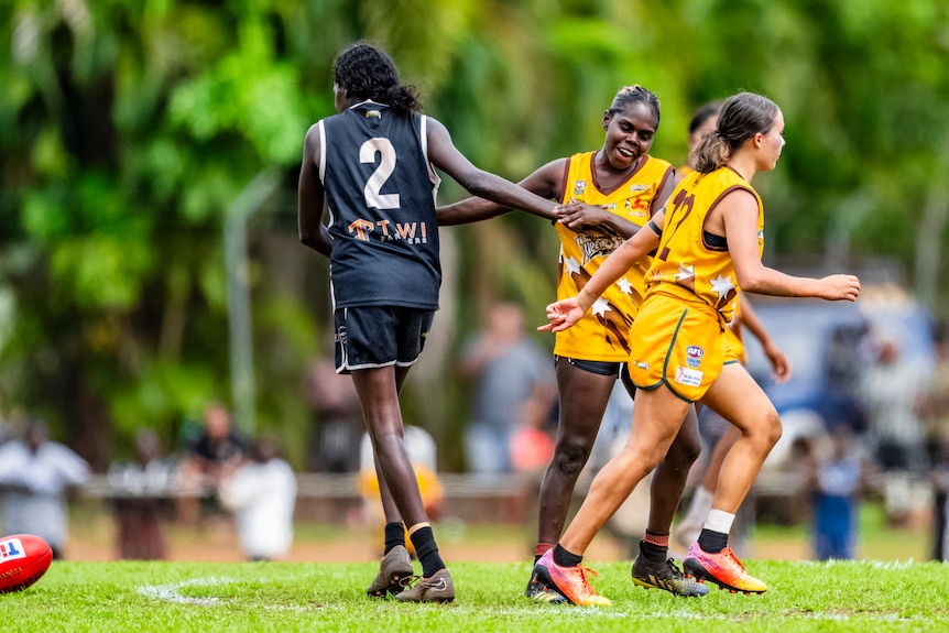 Two players from opposite teams embrace on the field.