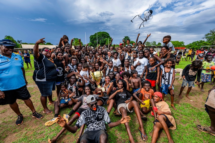 A big group of players and supporters pose for a group photo after the game.