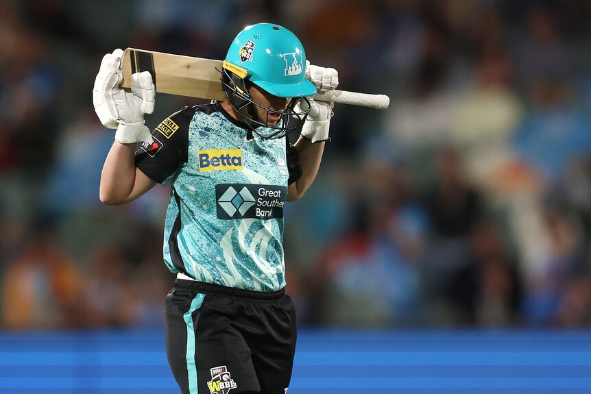 Hinkley holds her bat behind her neck and looks down as she walks off