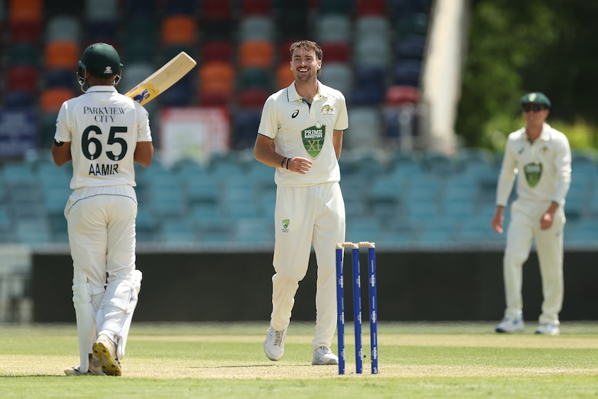 A Prime Minister's XI cricketer smiles as he looks down the wicket towards the batsman he has just dismissed.