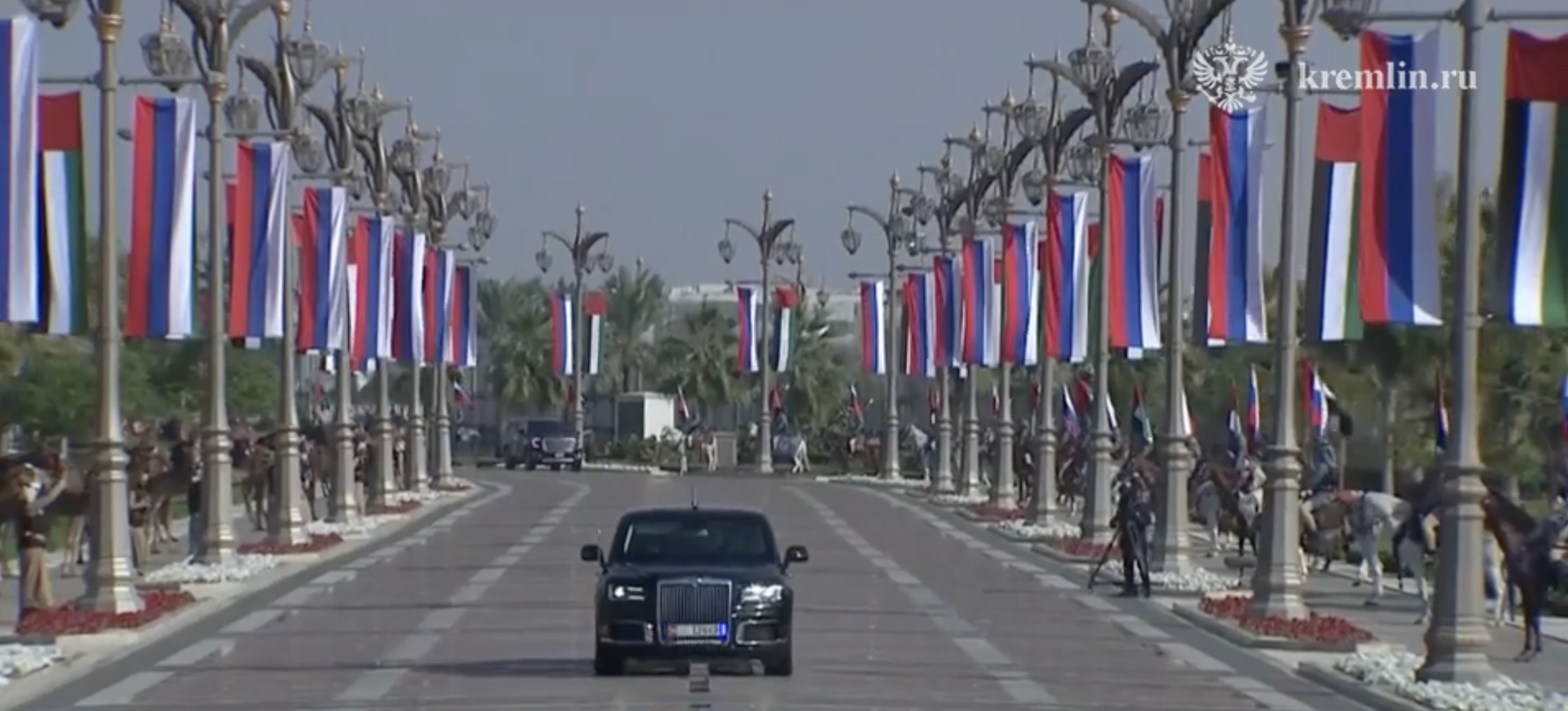 Putin's £1million limo going through the streets of Abu Dhabi lined with Russian flags, camels and horses