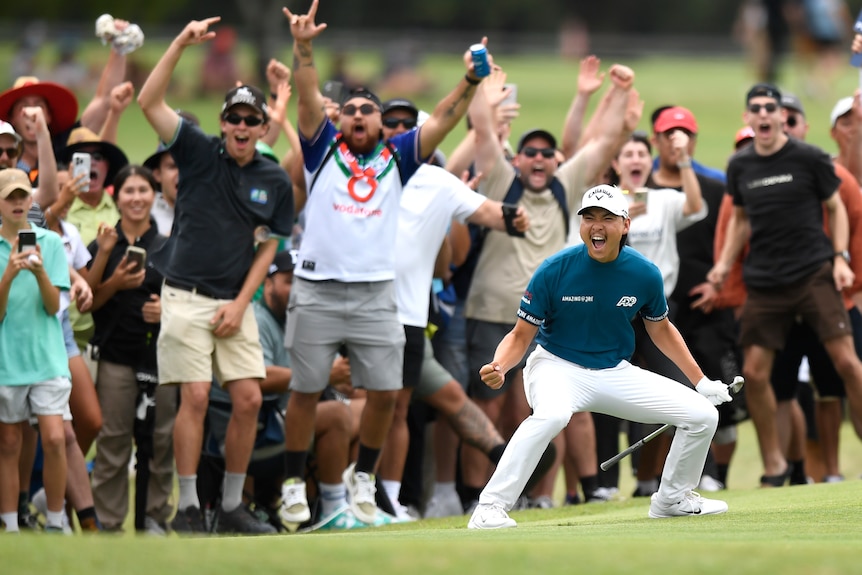 Min Woo Lee pumps both fists in celebration while fans behind him go crazy