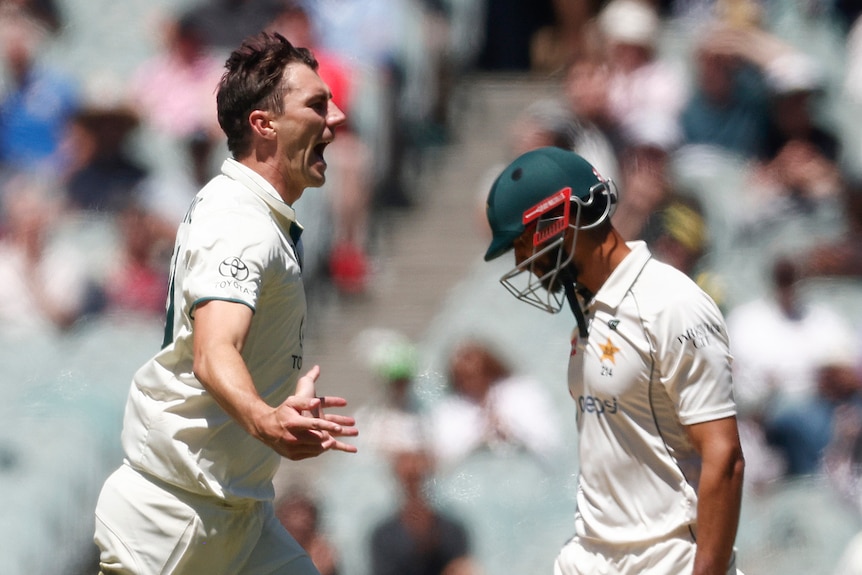 Shan Masood walks past a celebrating Pat Cummins