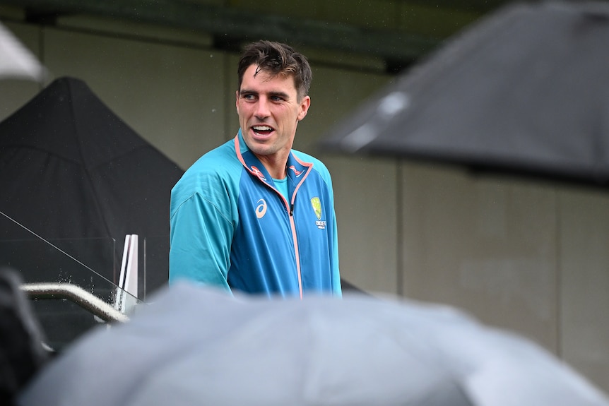 Pat Cummins walks among umbrellas