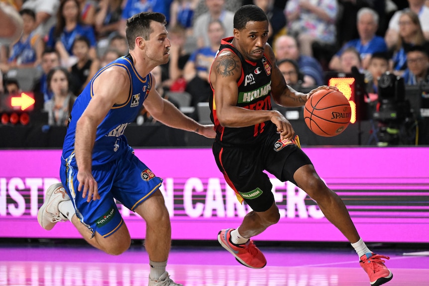 Bryce Cotton holds the ball while fending off his Brisbane Bullet's opponent.