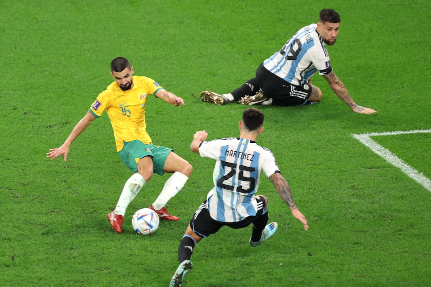 Aziz Behich is about to kick the ball as Martinez moves to stop him and Otamendi watches on his knees behind.