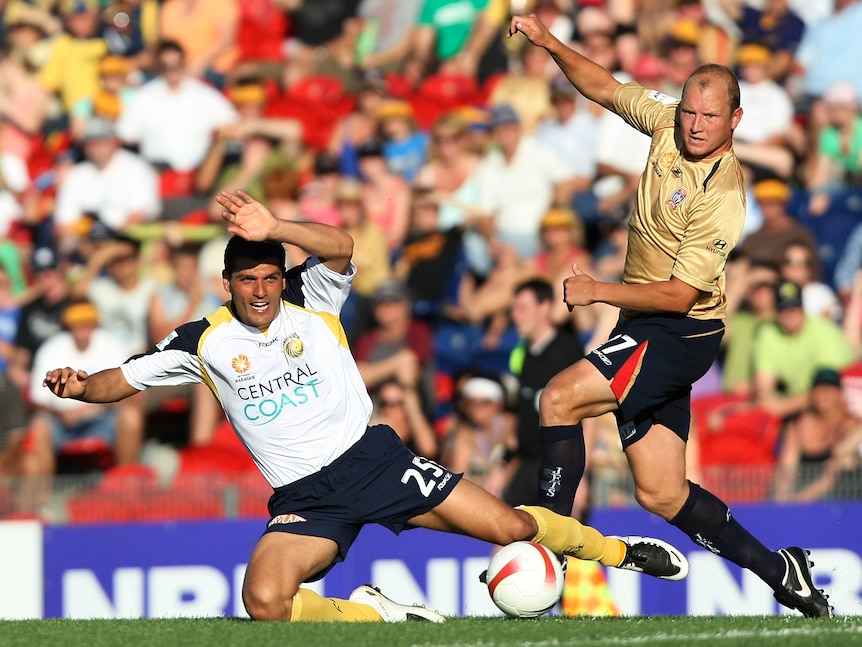 Soccer player Stephen Laybutt, right, playing against John Aloisi, who is on one knee to the left, in the A-League