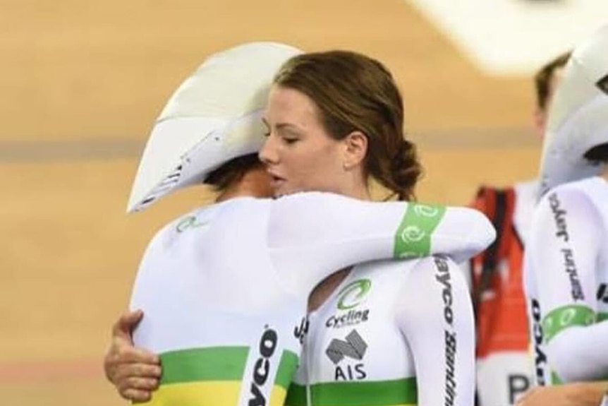 Two women in cycling hear hug at a velodrone