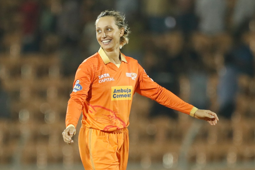 Ash Gardner, wearing orange, smiles after taking a wicket for Gujarat Giants in their WPL match against Delhi Capitals.