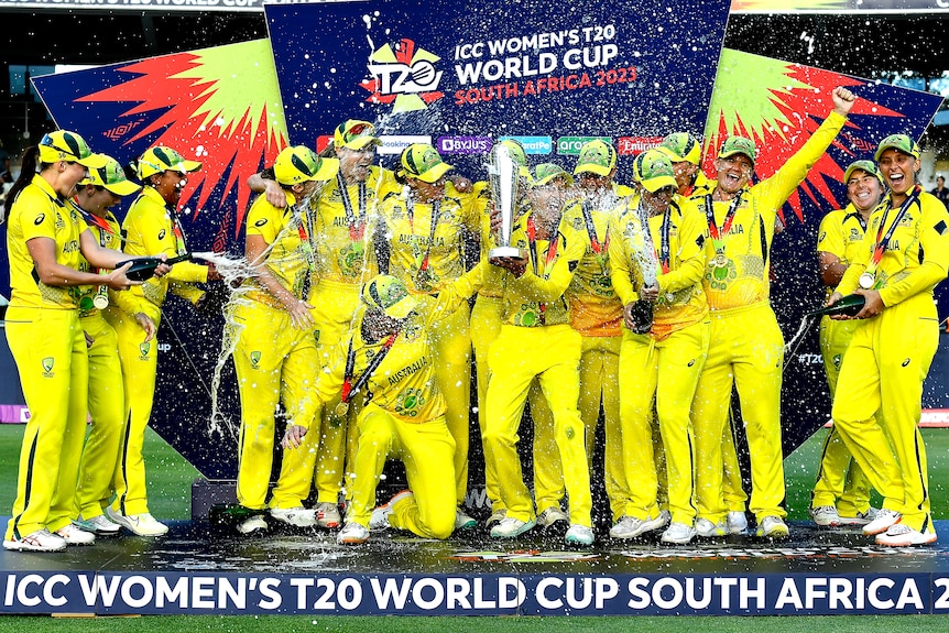 Aussie women's players stand on stage and spray each other with champagne