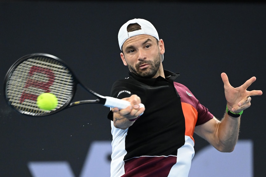 A man wearing a white cap holds onto a tennis racquet.