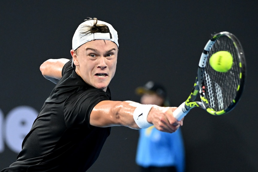 A man wearing a white cap holding a tennis racquet.
