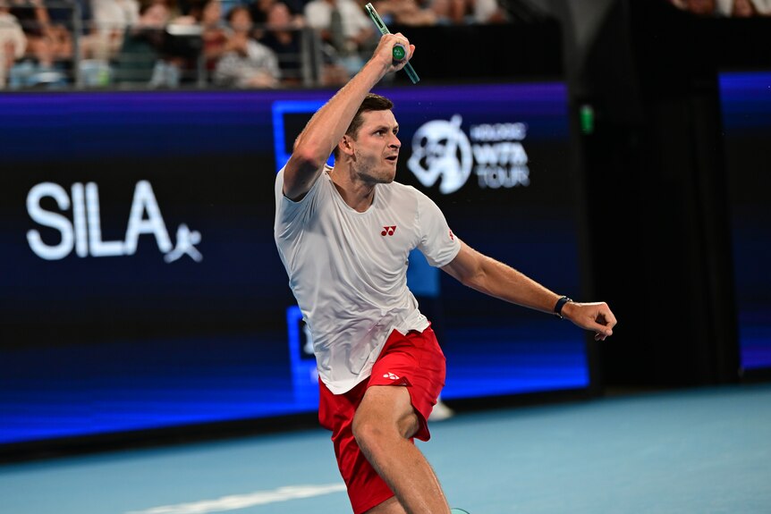 Hubert Hurkacz holding a racquet above his head. 