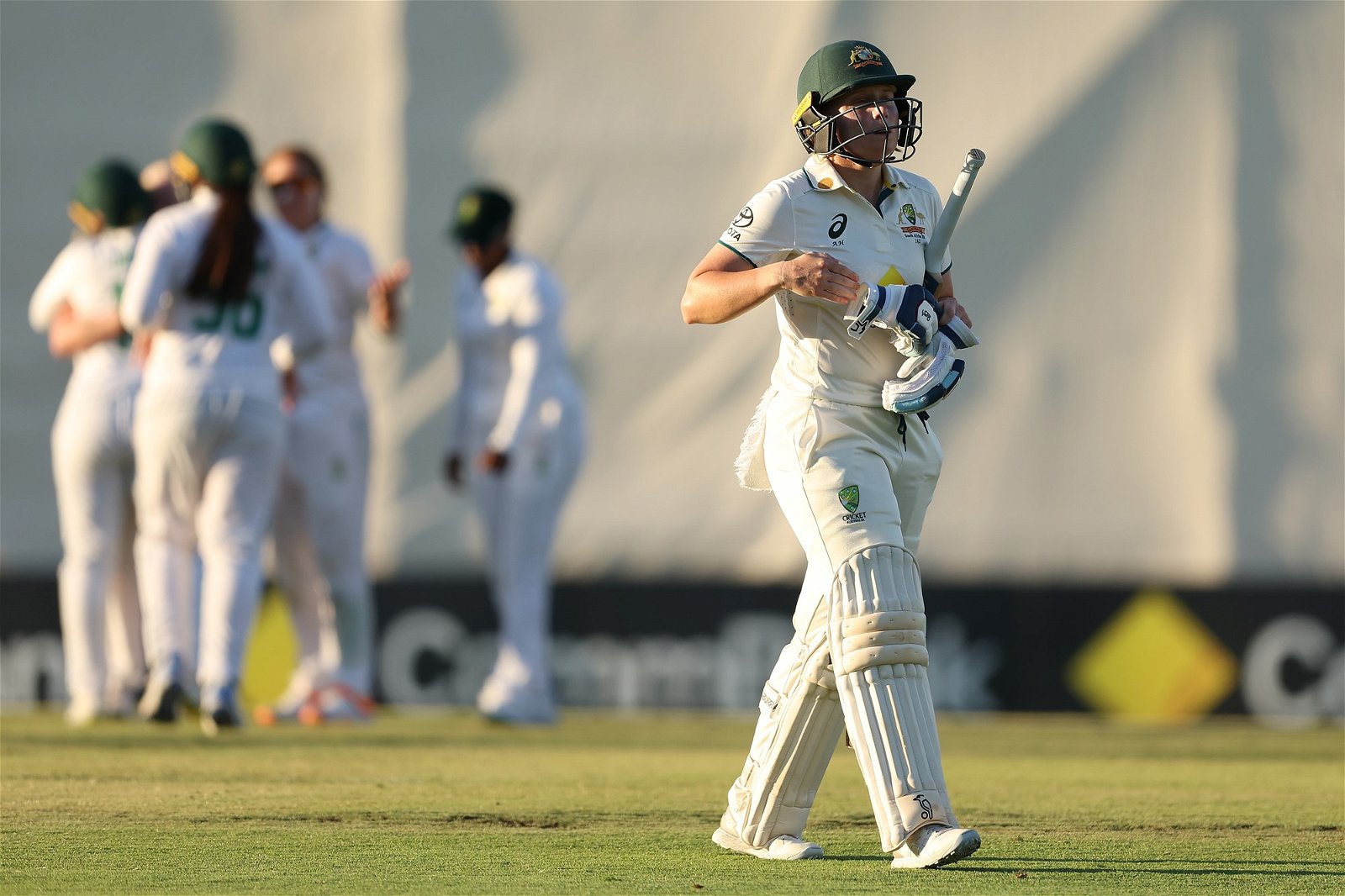 Australia batter Alyssa Healy walks off the field as South Africa celebrates behind her during a Test.