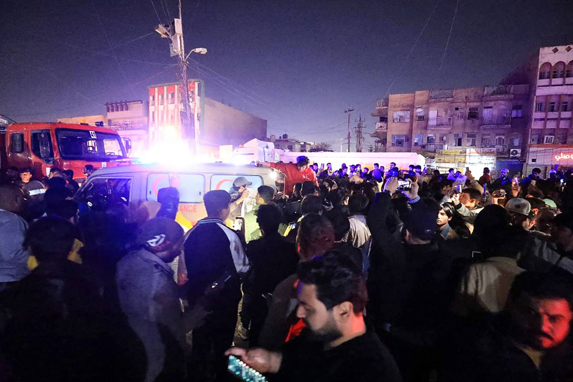 An ambulance and a fire truck rush to the scene where a vehicle was hit by a drone strike in Baghdad on Wednesday. Photo: AFP