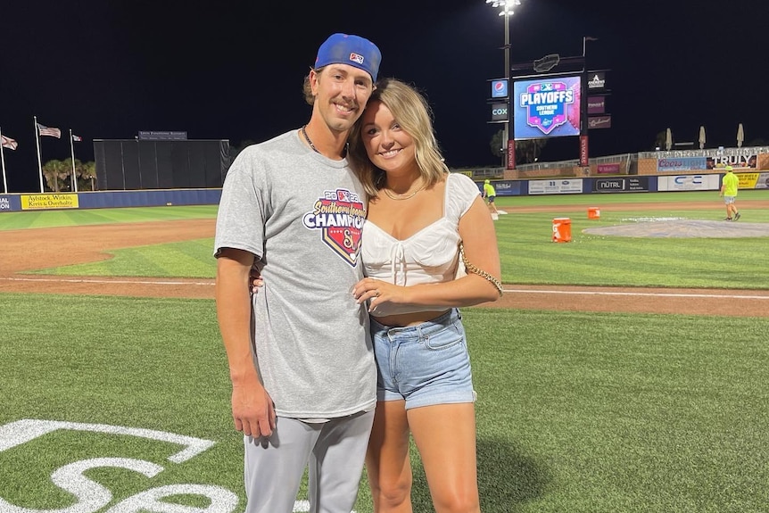 A young man and woman stand together smiling.
