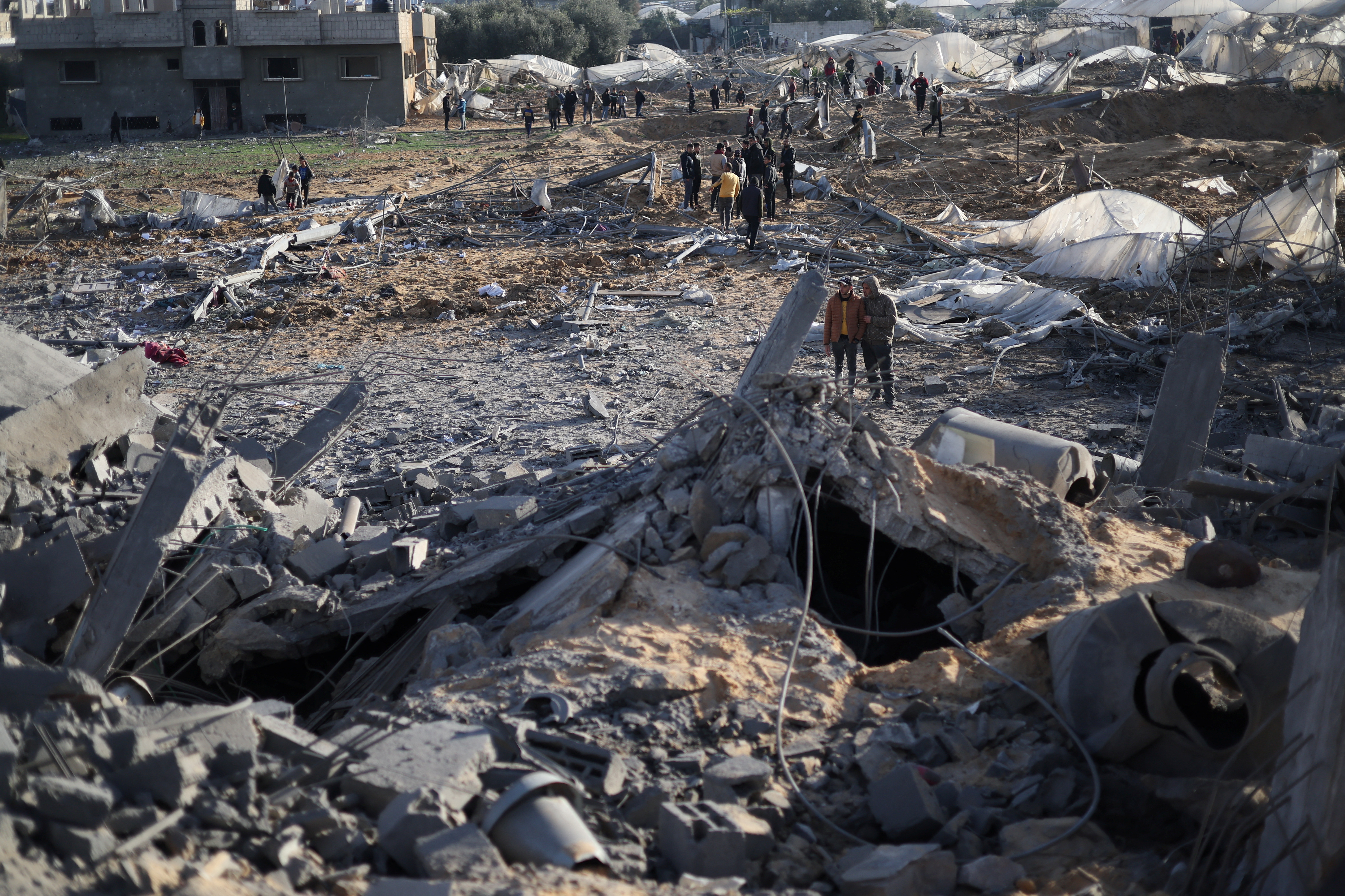 Palestinians inspect the site of an Israeli strike on a house in Rafah in the southern Gaza Strip, February 12, 2024