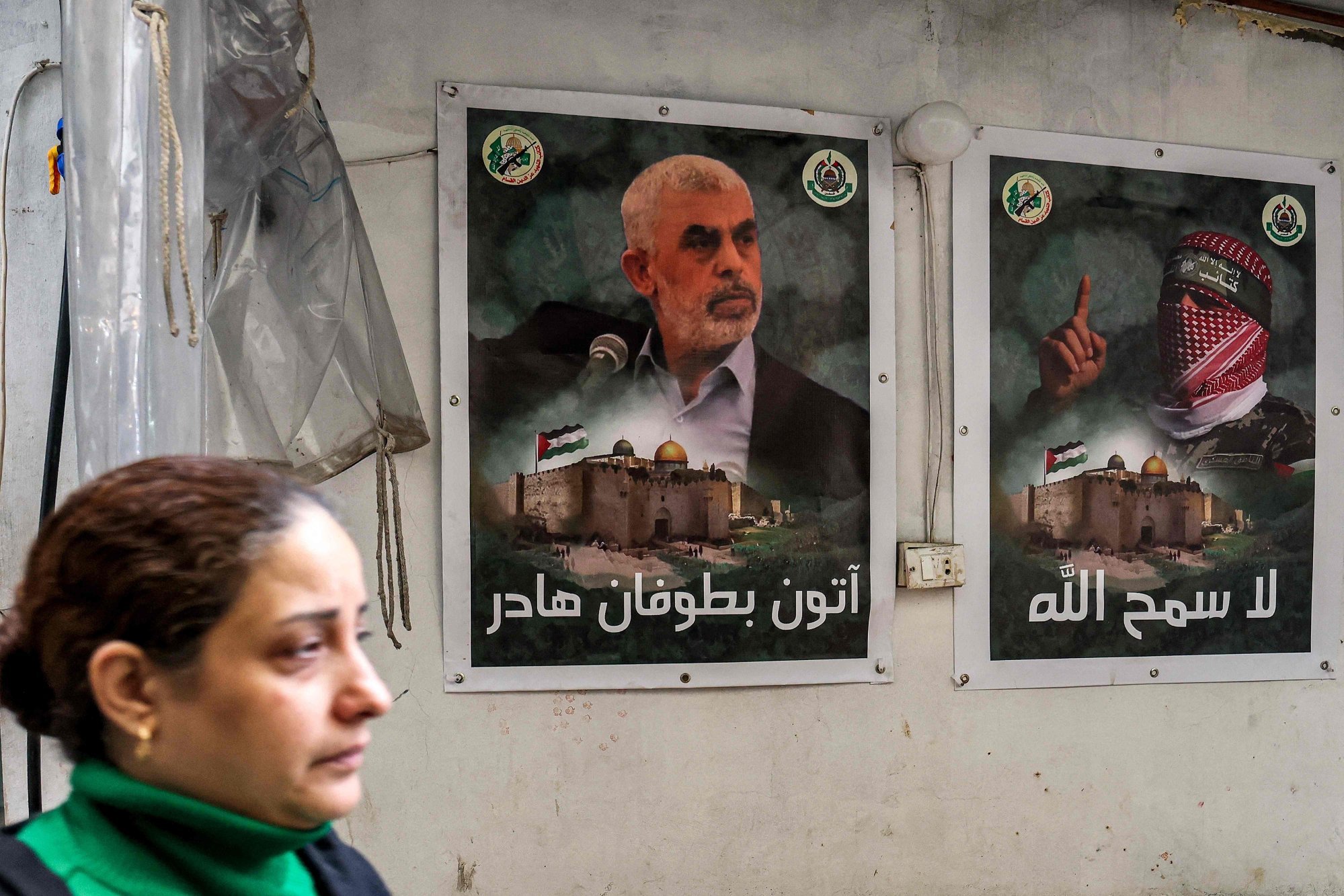A woman walks past posters depicting Yahya Sinwar (left), the head of the political wing of Hamas, and Abu Obeida (right), the masked spokesman of Hamas’ armed wing, in a camp for Palestinian refugees in Beirut on February 5. Photo: AFP