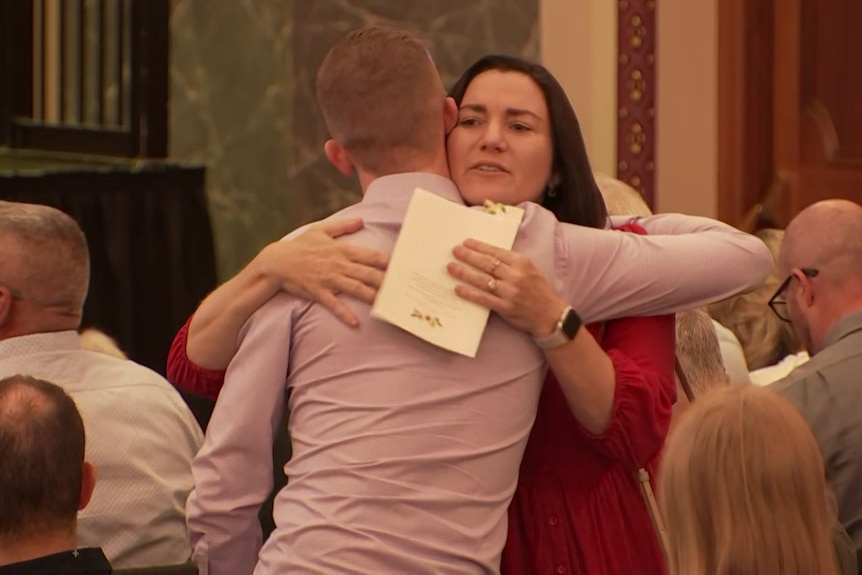 A woman hugs a person among others sitting in rows